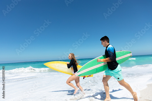 Photography Young couple running with surfboard
