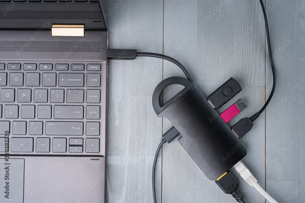 USB Type C adapter or hub connected to the laptop with various accessories - pendrives, hdmi, ethernet, cables. Flat lay top view.