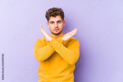 Young blond curly hair caucasian man isolated keeping two arms crossed, denial concept. © Asier