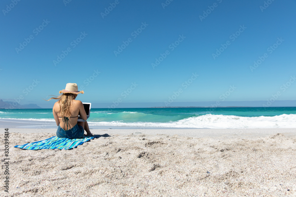 Rear view young woman with computer at the beach Rear view young woman with computer at the beach