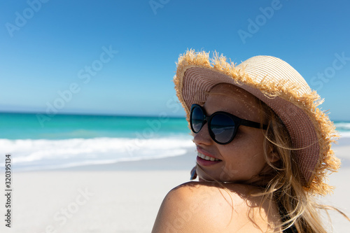 Young woman with hat smiling at the beach #320395134