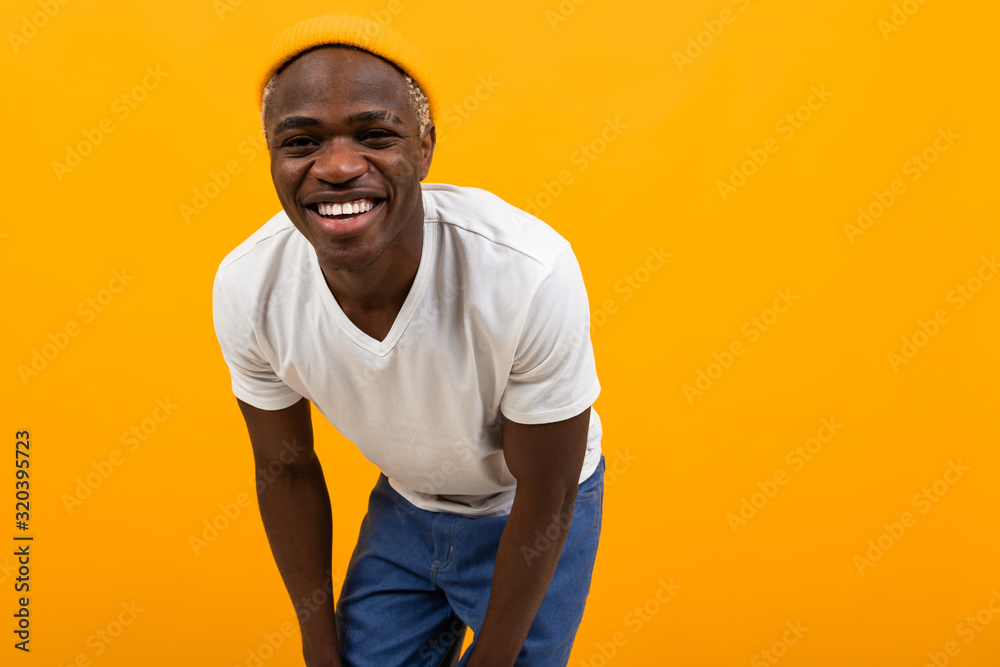 attractive african guy in a white t-shirt on a yellow background with copy space attractive african guy in a white t-shirt on a yellow background with copy space