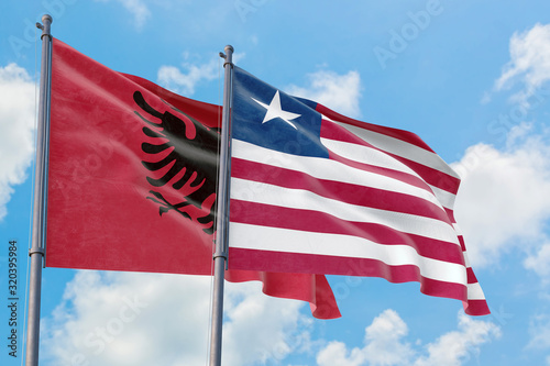 Liberia and Albania flags waving in the wind against white cloudy blue sky together. Diplomacy concept  international relations.