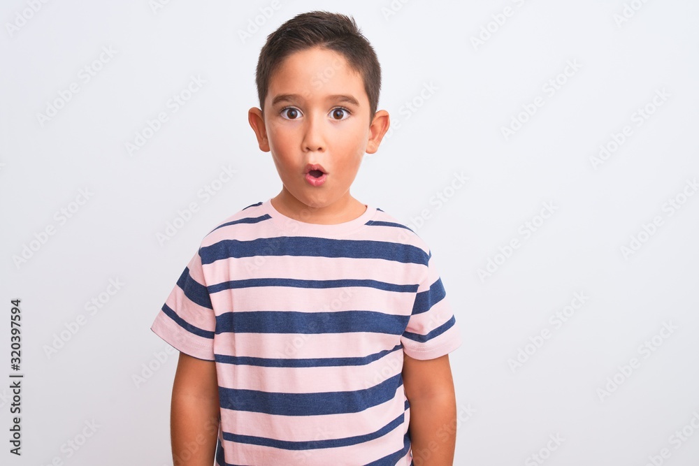 Beautiful kid boy wearing casual striped t-shirt standing over isolated white background afraid and shocked with surprise expression, fear and excited face. Beautiful kid boy wearing casual striped t-shirt standing over isolated white background afraid and shocked with surprise expression, fear and excited face.