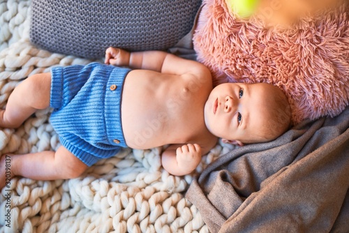 Adorable baby lying down on the sofa over blanket at home. Newborn relaxing and resting comfortable