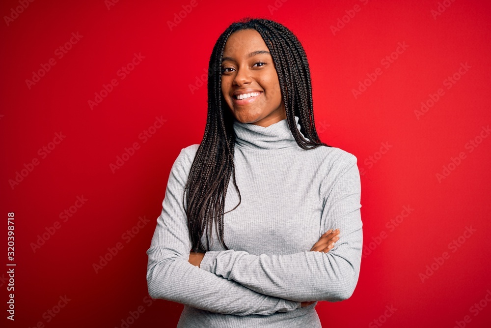Young african american woman wearing turtleneck sweater over red isolated background happy face smiling with crossed arms looking at the camera. Positive person. Young african american woman wearing turtleneck sweater over red isolated background happy face smiling with crossed arms looking at the camera. Positive person.