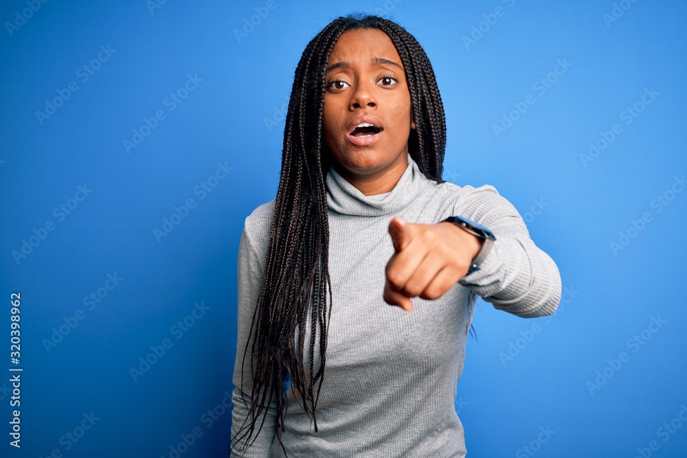 Young african american woman standing wearing casual turtleneck over blue isolated background pointing displeased and frustrated to the camera, angry and furious with you Young african american woman standing wearing casual turtleneck over blue isolated background pointing displeased and frustrated to the camera, angry and furious with you