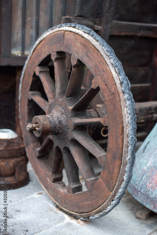 A photo of a traditional wooden wagon wheel seen on a countryside farm