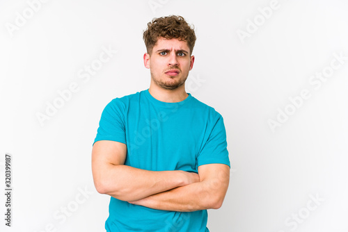 Young blond curly hair caucasian man isolated unhappy looking in camera with sarcastic expression.