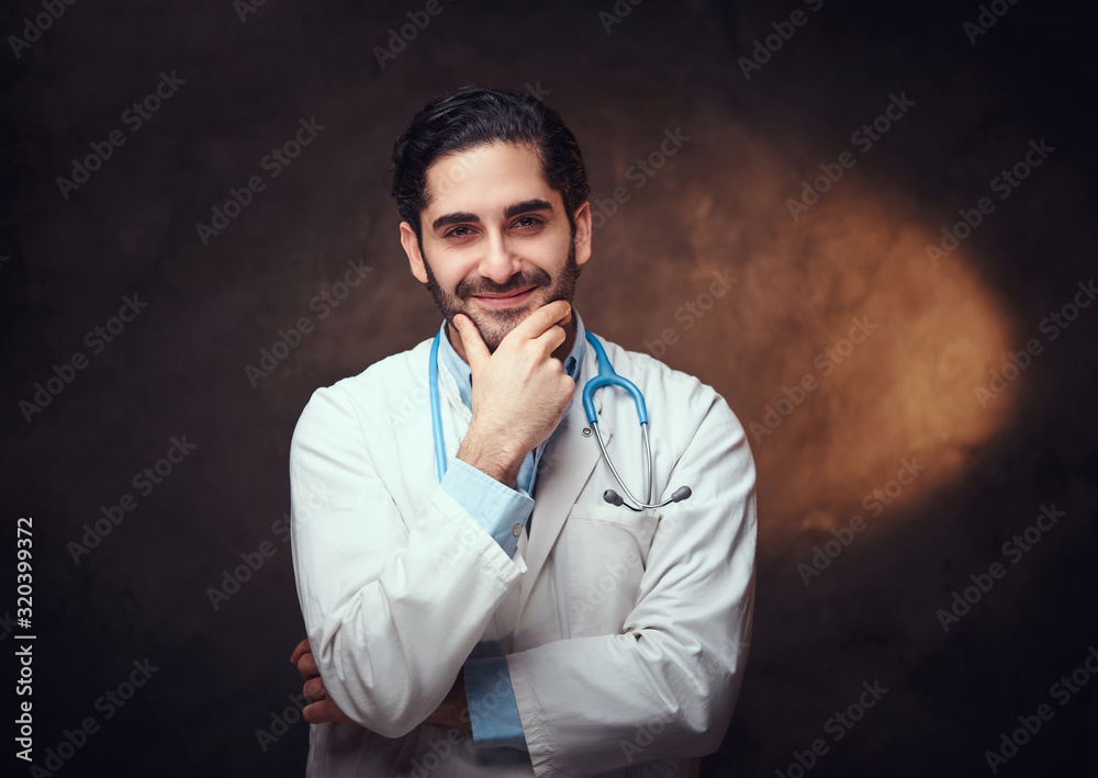Handsome bearded man in doctor's uniform is posing for photographer over dark background. Handsome bearded man in doctor's uniform is posing for photographer over dark background.