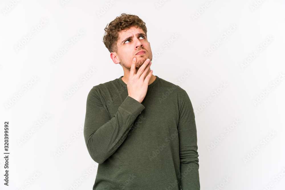 Young blond curly hair caucasian man isolated thinking and looking up, being reflective, contemplating, having a fantasy.