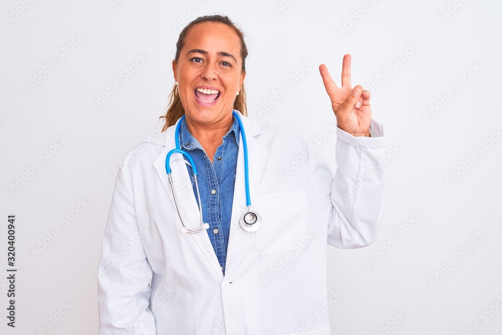 Middle age mature doctor woman wearing stethoscope over isolated background smiling with happy face winking at the camera doing victory sign. Number two. Middle age mature doctor woman wearing stethoscope over isolated background smiling with happy face winking at the camera doing victory sign. Number two.