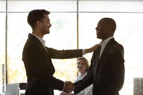 Boss handshaking with african team leader thanking for successful work photo