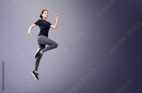 Fototapeta Naklejka Na Ścianę i Meble -  Full length portrait of fitness woman in sportswear jumping.