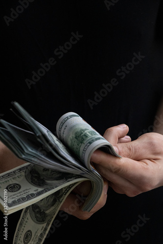 American dollars in male hands on a black background. One hundred dollar bills. Money.