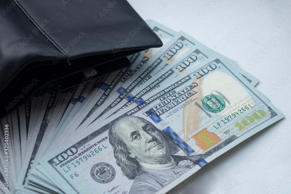 American dollars on a white background. One hundred dollar bills. Coins on the table. I put money in my wallet. Rich. American dollars on a white background. One hundred dollar bills. Coins on the table. I put money in my wallet. Rich.
