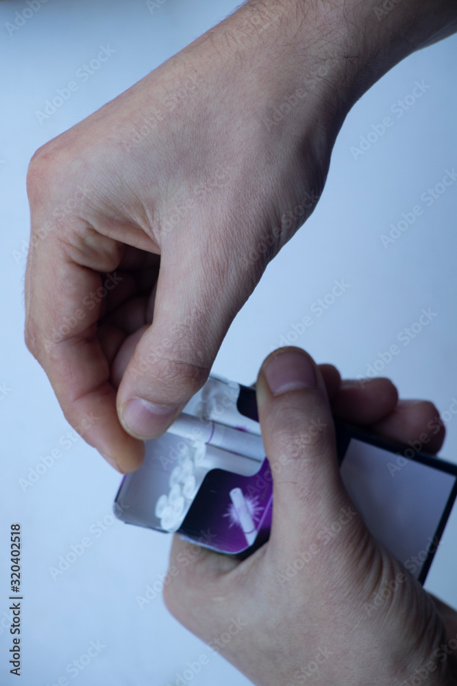 A man beats a cigarette. The beginning of smoking. Cigarette in the lips and a lighter in the hands. I get one pack of cigarett.
