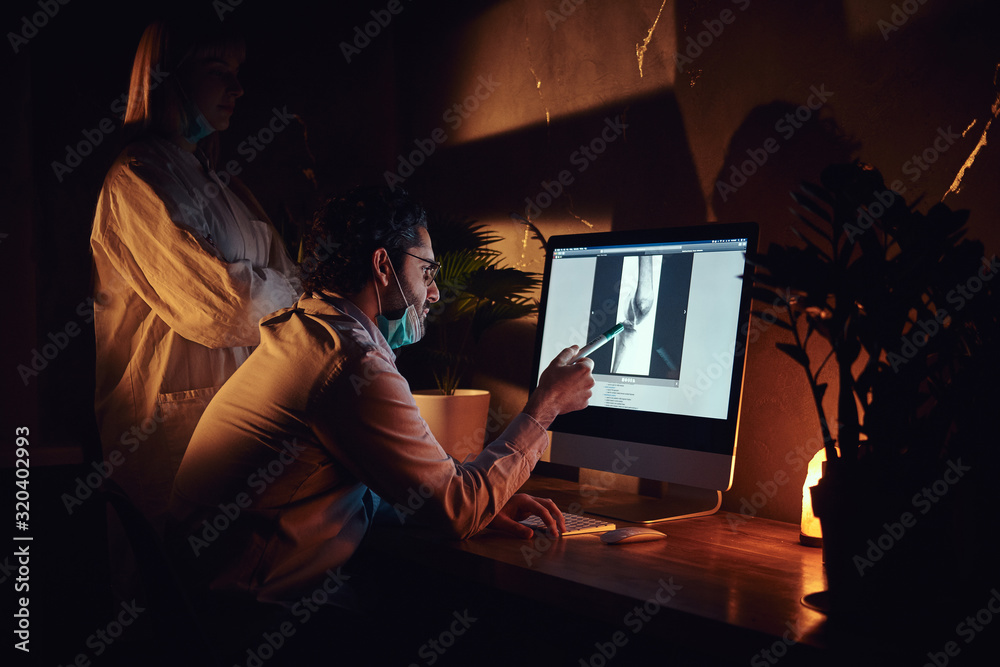 At the dark office experienced doctor is learning young intern how to read x-ray. At the dark office experienced doctor is learning young intern how to read x-ray.