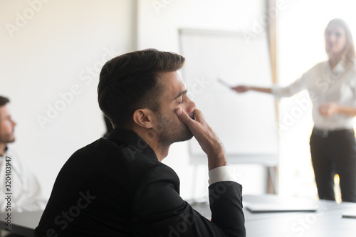 Bored employee fall asleep during seminar or presentation in office photo