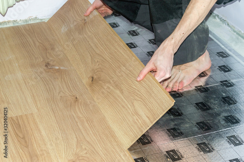 Worker installing new wooden laminate flooring.