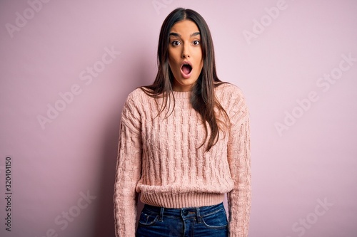 Young beautiful brunette woman wearing casual sweater over isolated pink background afraid and shocked with surprise and amazed expression, fear and excited face.