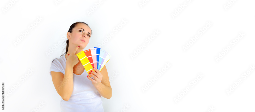 Girl designer stands with a color palette and chooses a color for painting the walls of the house. Repair of the premises. Isolated on a white background. Girl designer stands with a color palette and chooses a color for painting the walls of the house. Repair of the premises. Isolated on a white background.