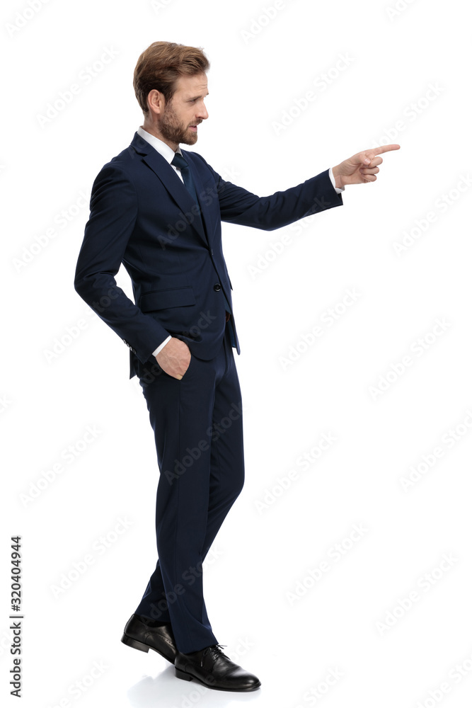 young businessman in navy blue suit pointing finger to side young businessman in navy blue suit pointing finger to side