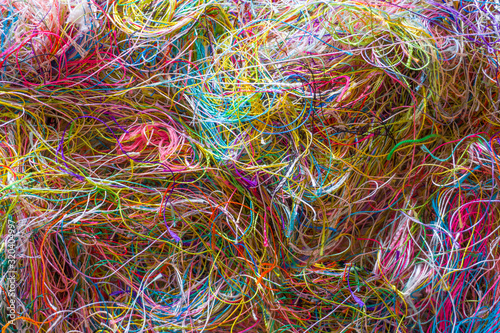Multi-colored tangled threads abstract texture pattern background. Macro shot of colorful needlecraft silk thread ropes. Colored natural thread pile for sewing clothe scattered randomly like spaghetti photo