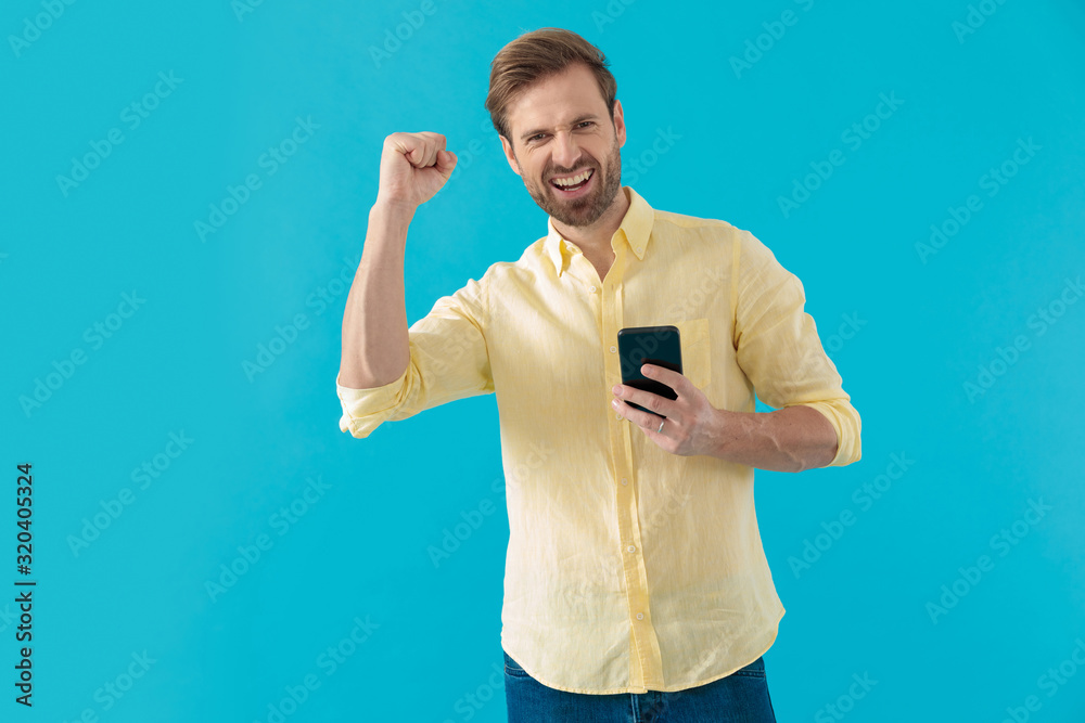 Happy casual man laughing and celebrating, holding a phone Happy casual man laughing and celebrating, holding a phone