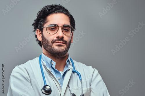 Young handsome doctor is posing for photographer over light background.