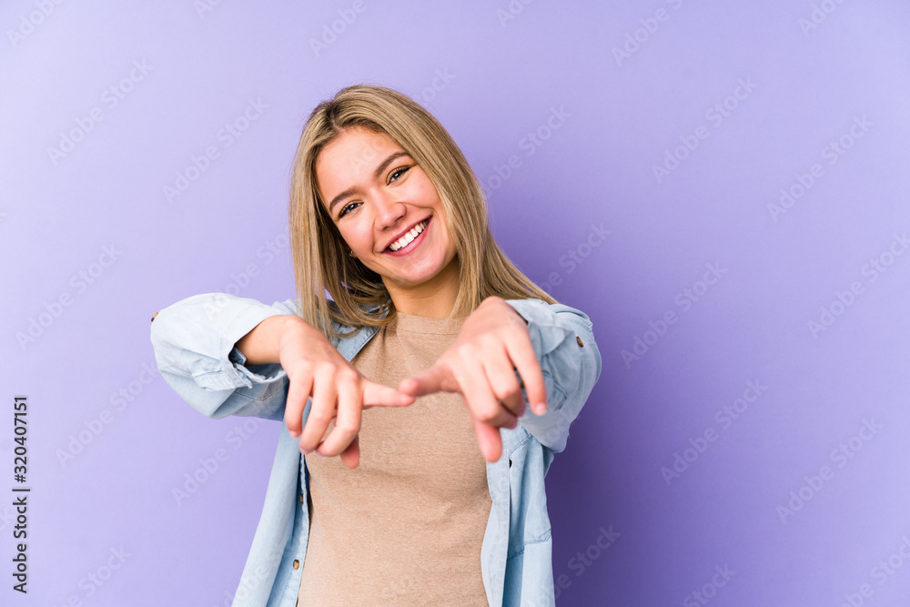 Young blonde caucasian woman isolated cheerful smiles pointing to front. Young blonde caucasian woman isolated cheerful smiles pointing to front.