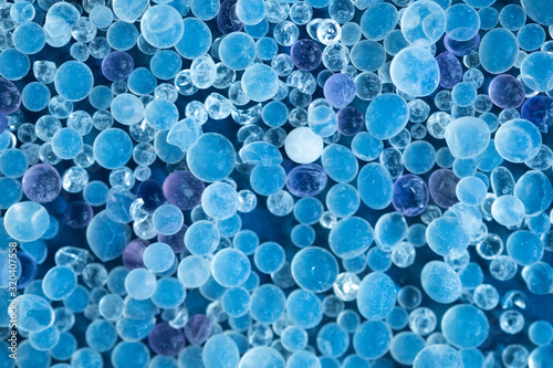 Close up - Pile of silica gel on blue background, Desiccant used in industrial, moisture protection. Desiccant Silica Gel (Moisture Absorber) Background. Blue and White Translucent Crystals Texture photo