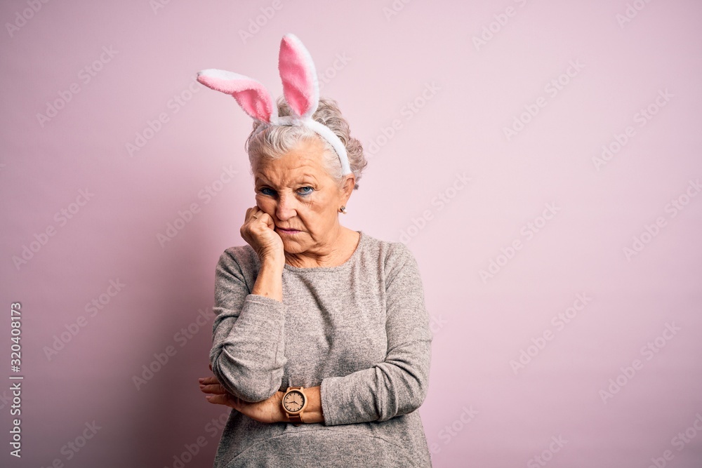 Senior beautiful woman wearing bunny ears standing over isolated pink background thinking looking tired and bored with depression problems with crossed arms.