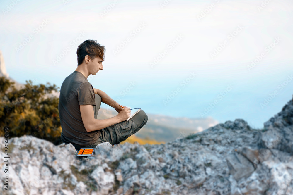 Young Man sitting on rocks and Painting Mountains and sea