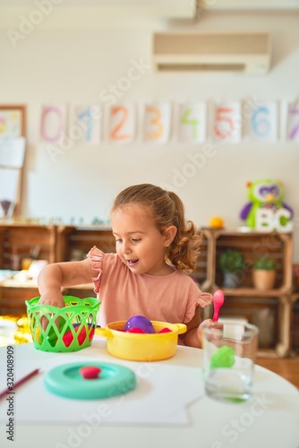 Beautiful blond toddler girl playing meals using plastic food at kindergarten