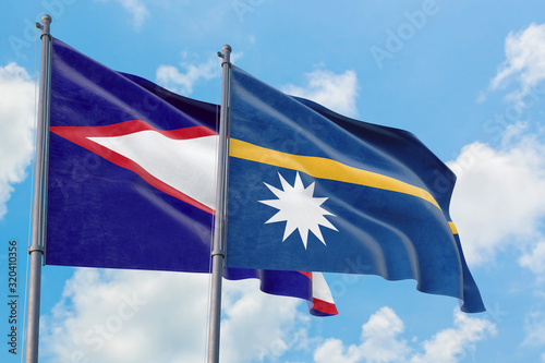 Nauru and American Samoa flags waving in the wind against white cloudy blue sky together. Diplomacy concept, international relations.