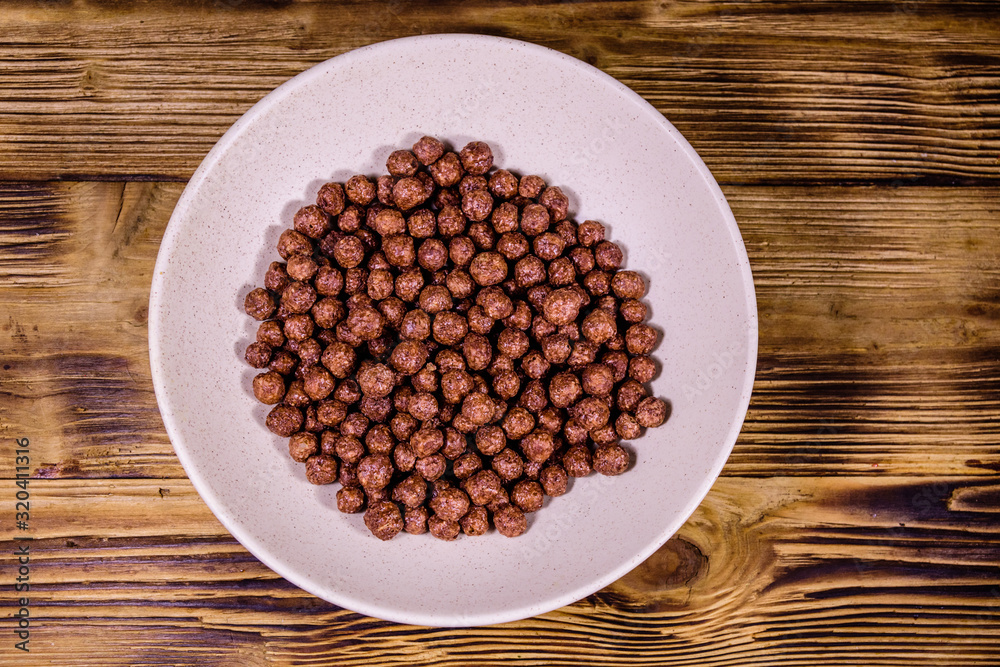 Ceramic plate with chocolate cereal balls on wooden table. Top view Ceramic plate with chocolate cereal balls on wooden table. Top view