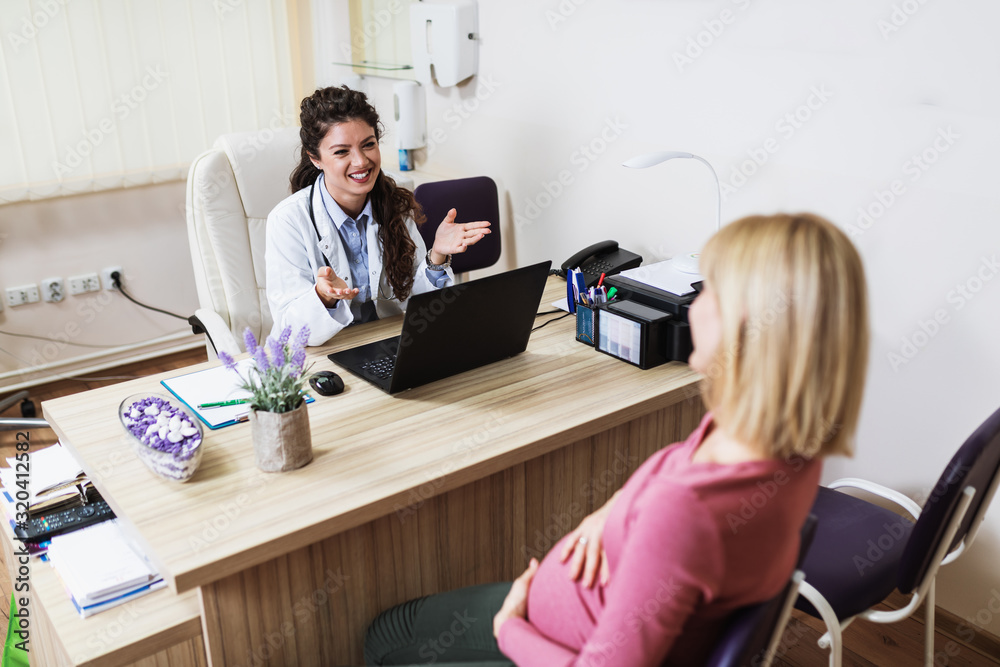 Pregnant woman talking with her doctor at clinic. Pregnant woman talking with her doctor at clinic.