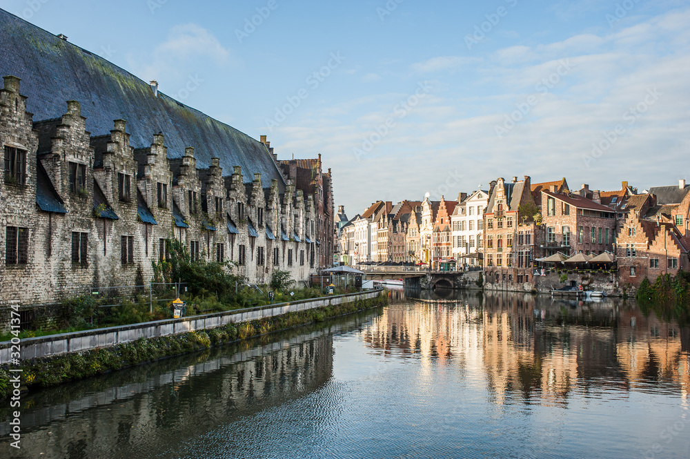 Naklejka premium Wibrujący widok na ulicę w centrum Gandawy, stolicy prowincji Flandria Wschodnia w Belgii, wzdłuż rzeki Leie