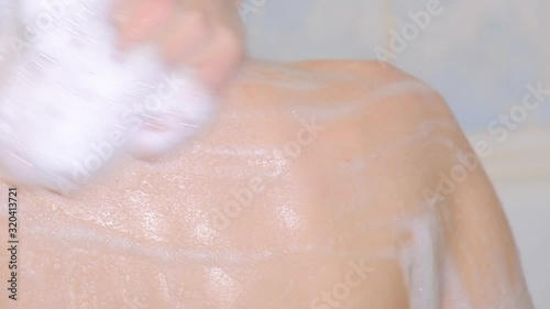 Woman washes shower soap foam, slow movement hand on shoulder close-up