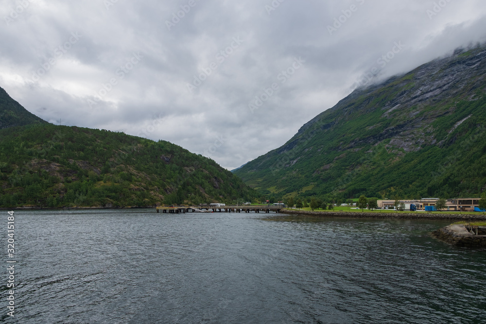 Obraz premium Blue water of Geirangerfjord as seen from the town Hellesylt, More og Romsdal, Norway. July 2019