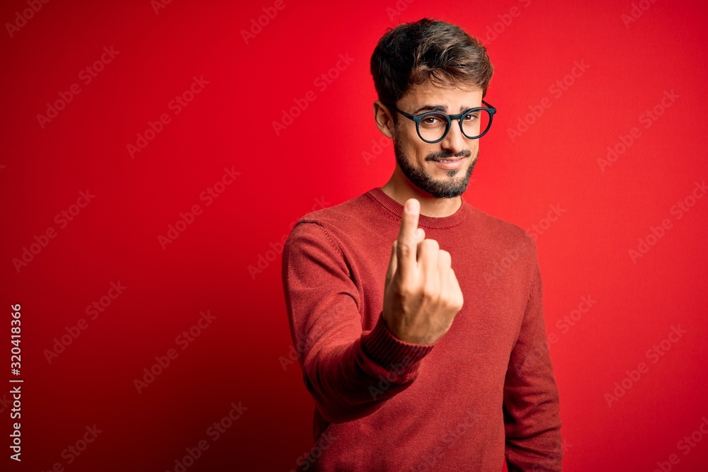 Young handsome man with beard wearing glasses and sweater standing over red background Beckoning come here gesture with hand inviting welcoming happy and smiling Young handsome man with beard wearing glasses and sweater standing over red background Beckoning come here gesture with hand inviting welcoming happy and smiling