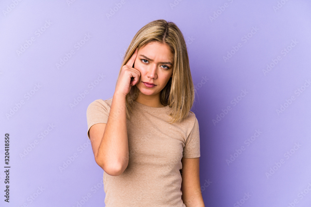 Young blonde caucasian woman isolated pointing temple with finger, thinking, focused on a task.