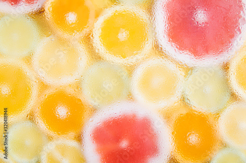 Pattern of different sliced citrus fruits on yellow background. Out of focus, water drops texture