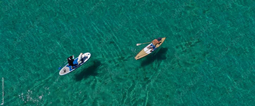 Aerial drone ultra wide photo of friends practising in SUP or Stand Up Paddle in tropical exotic bay with turquoise sea