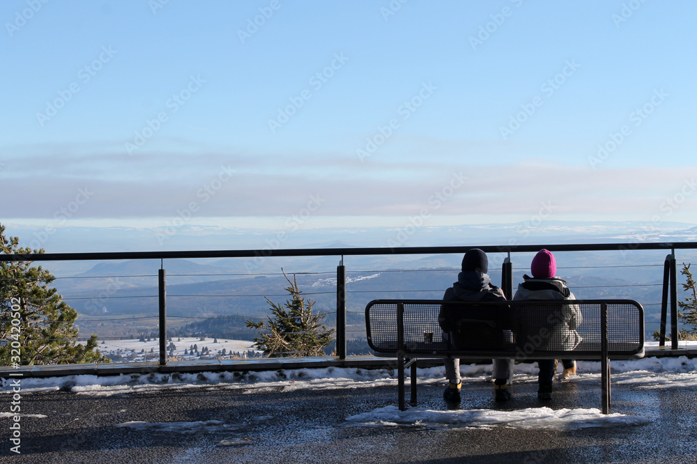 Two people sitting side by side with a beautiful wide view on top of the moutain Two people sitting side by side with a beautiful wide view on top of the moutain