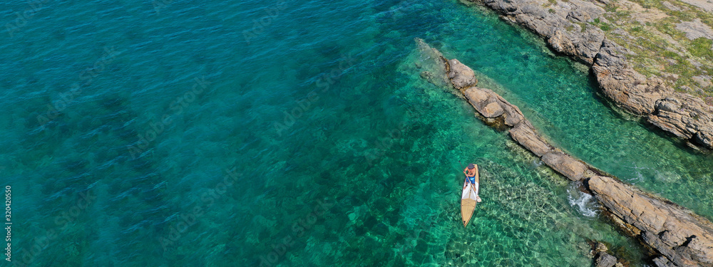 Aerial drone ultra wide top down photo of male Stand Up Paddle board surfer paddling in tropical exotic sea with turquoise calm water
