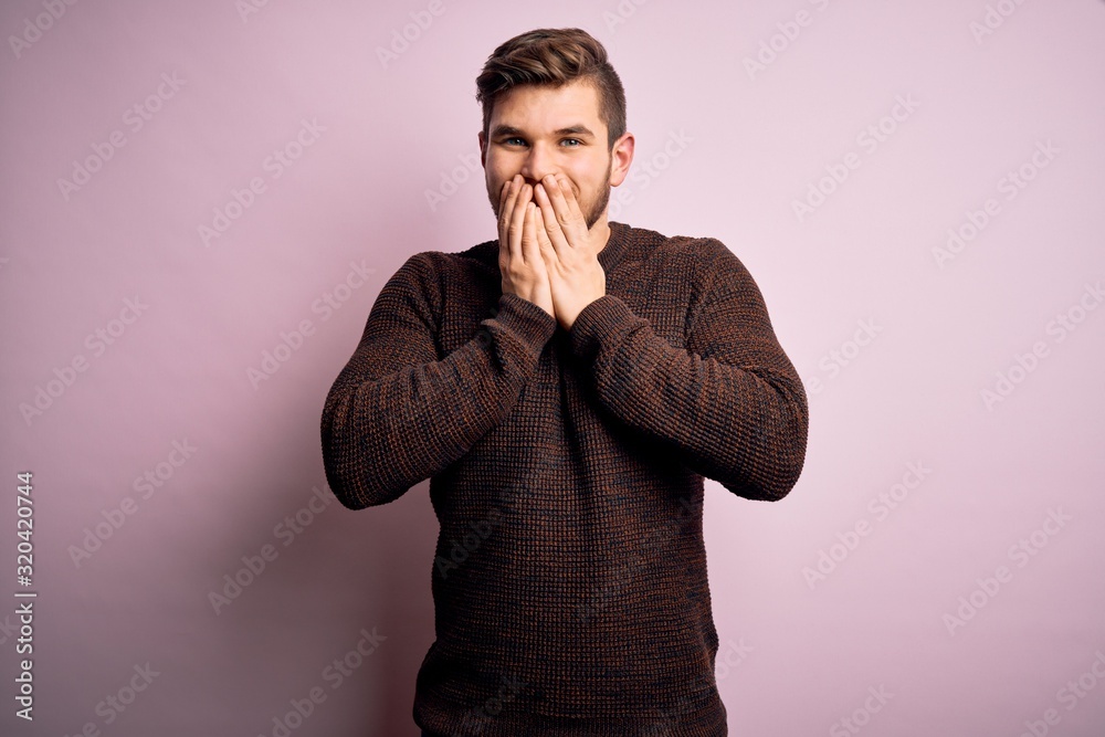 Young blond man with beard and blue eyes wearing casual sweater over pink background laughing and embarrassed giggle covering mouth with hands, gossip and scandal concept Young blond man with beard and blue eyes wearing casual sweater over pink background laughing and embarrassed giggle covering mouth with hands, gossip and scandal concept