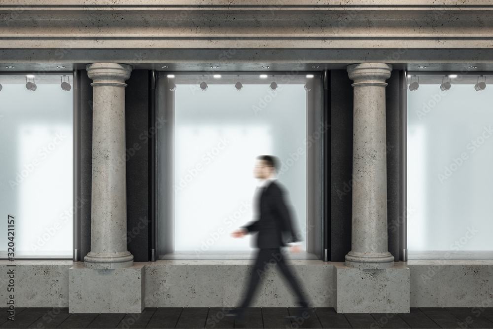 Businessman walking down street near shop window with blank poster.