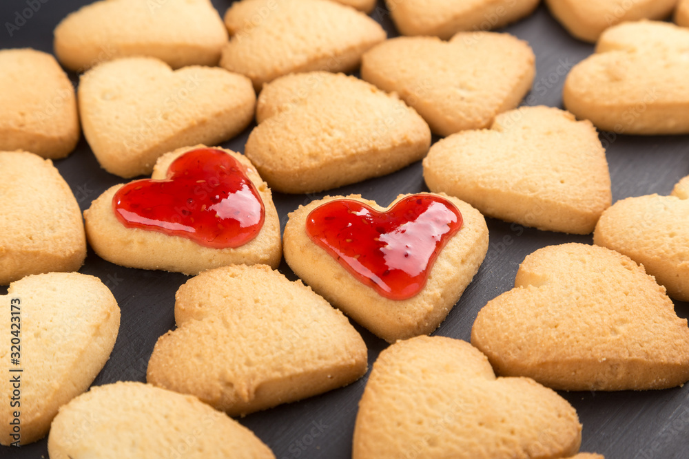 Heart shaped cookies decorated for Valentine's Day. Free space for text. Two heart shaped cookies with jam on a black wooden table. Like postcard Heart shaped cookies decorated for Valentine's Day. Free space for text. Two heart shaped cookies with jam on a black wooden table. Like postcard